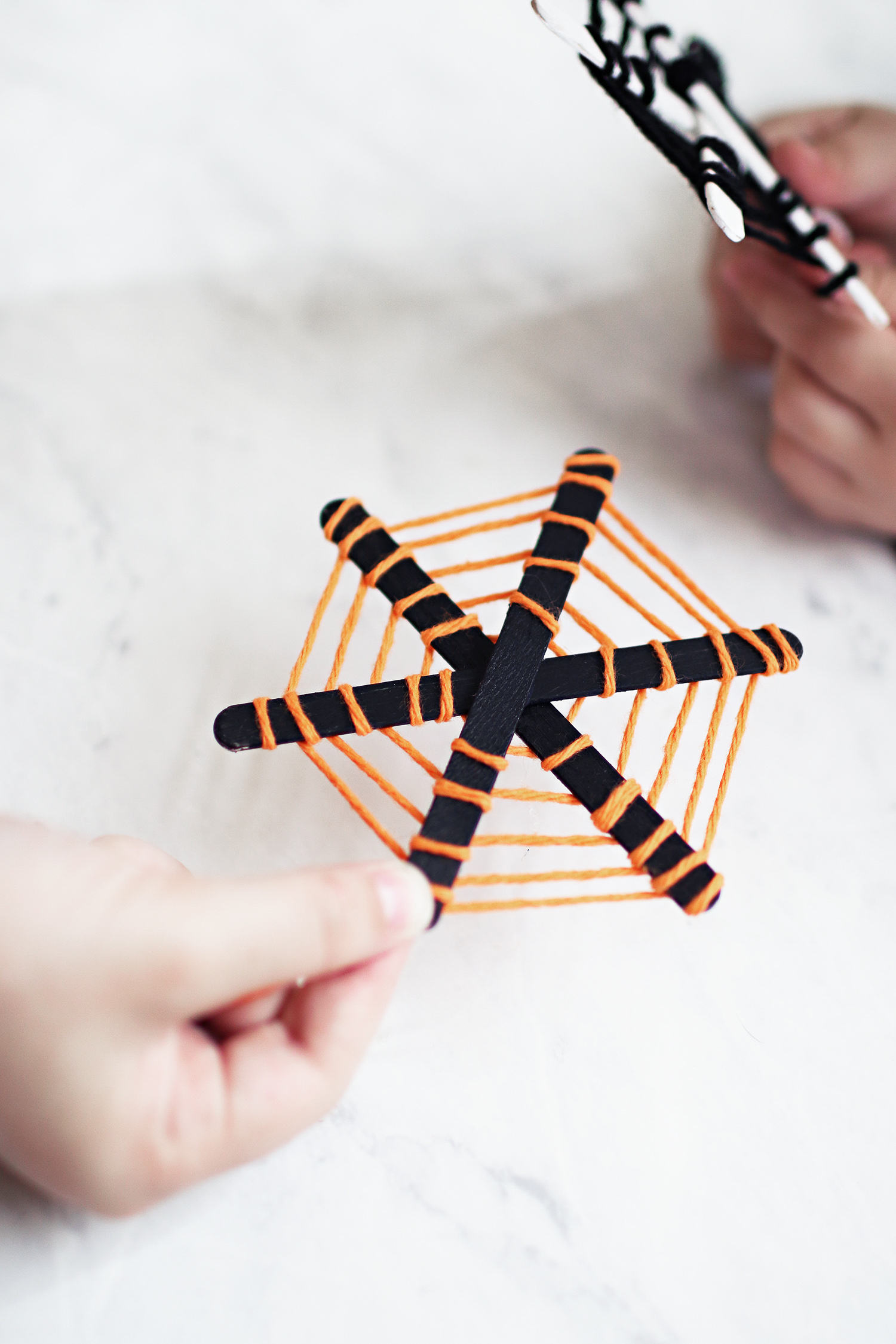 Halloween craft for the kids and these DIY Popsicle stick spiderwebs are the cutest! Our kiddos love hanging them up each year over our kitchen table. Catch the walk through over at Haus of Layne! #Halloween #HalloweenCraft #KidsCraftIdeas #HalloweenDecorIdeas #HalloweenIdeas